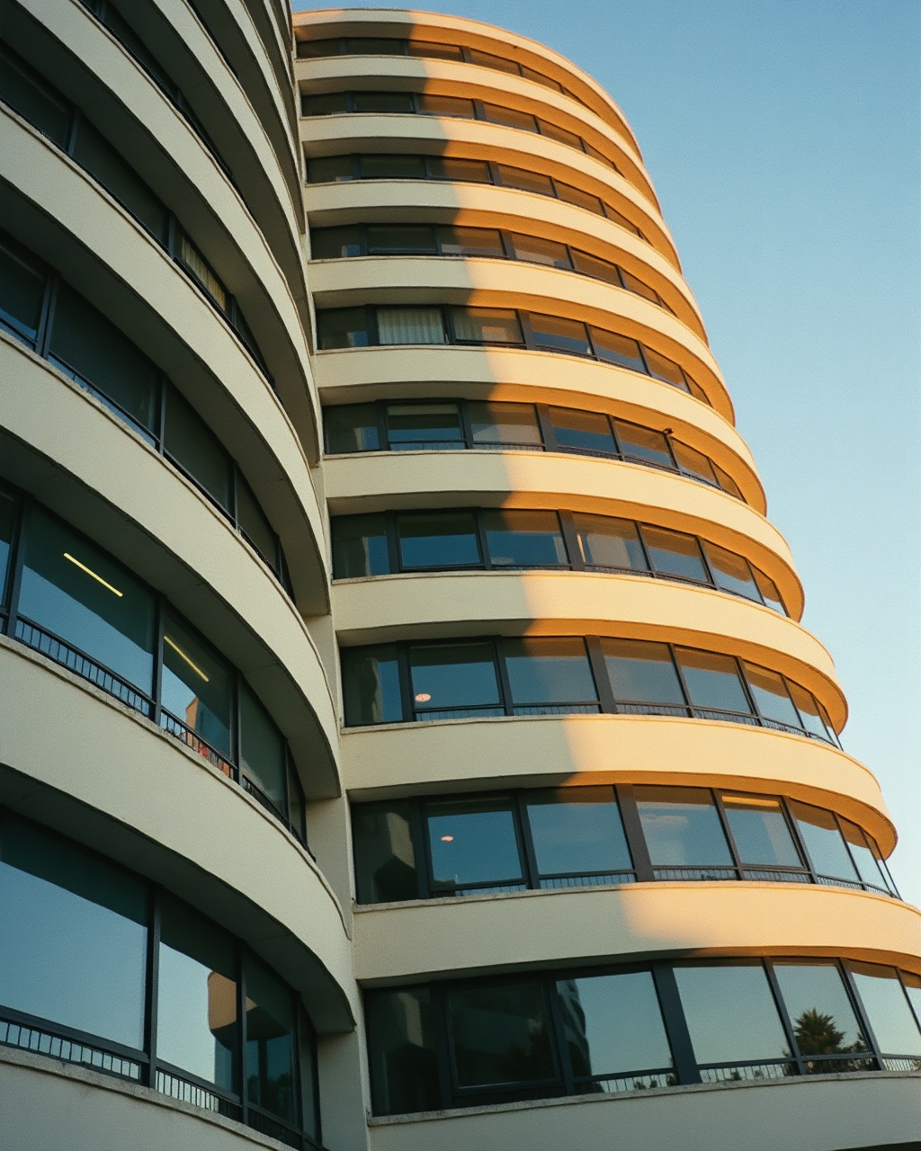 Close-up of a curved concrete and glass tower facade catching late-afternoon light